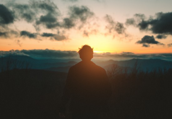 海から昇ってくる太陽を見つめる人