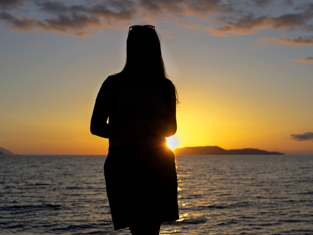 海にしずむ夕日をながめる人