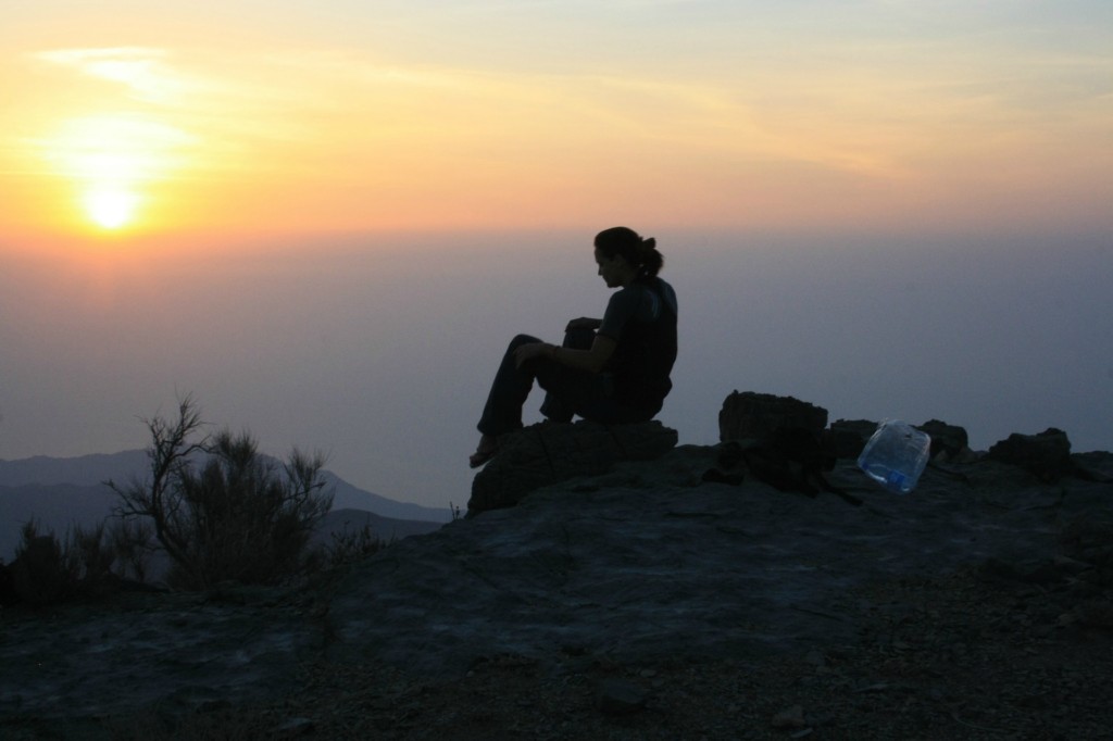 山頂から朝日を見る人
